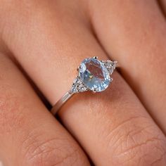 a woman's engagement ring with an aqua blue topazte and diamond accents