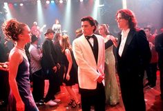 two men in tuxedos talking to each other on the dance floor