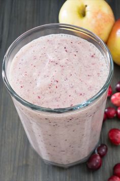 an apple and cranberry smoothie in a glass next to some cherries