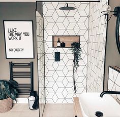 a bathroom with black and white tiles on the walls, a shower head, and a mirror