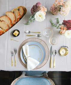 the table is set with silverware, bread and flowers in vases on it