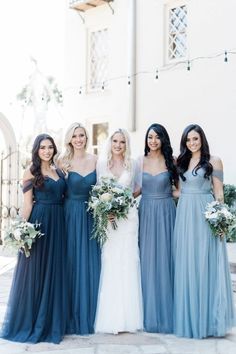 a group of women standing next to each other wearing dresses and holding bouquets in their hands