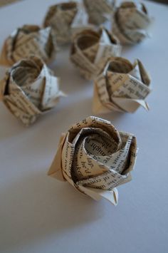 several rolled up origami flowers sitting on top of a white tablecloth covered surface