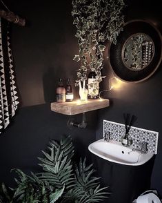 a bathroom with black walls and green plants on the shelf next to the white sink