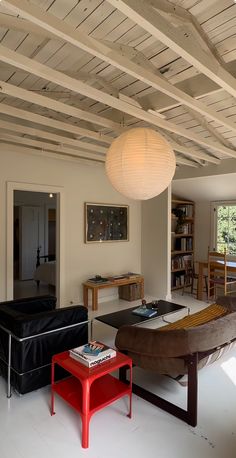 a living room filled with furniture next to a book shelf and lamp above the couch