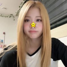 a girl with a yellow star on her nose is looking at the camera and she has long blonde hair