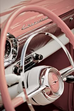 the steering wheel and dashboard of an old classic car with pink leather dash tape on it