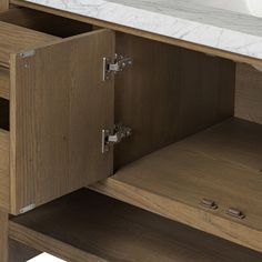 a bathroom vanity with marble counter top and wooden cabinet doors, including one drawer open