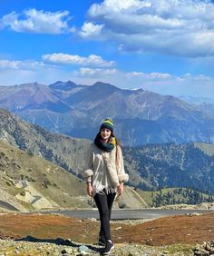 a woman standing on top of a mountain with mountains in the background