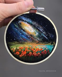 a hand is holding up a painted ornament with an image of the night sky