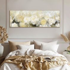 a large painting on the wall above a bed with white and yellow flowers in vases