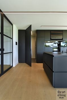 an empty kitchen with black cabinets and wood flooring is seen in this image from the hallway to the living room