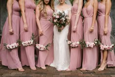 a group of women standing next to each other wearing pink bridesmaid gowns