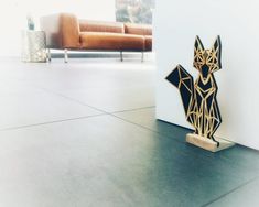 a wooden sculpture sitting on top of a floor next to a couch