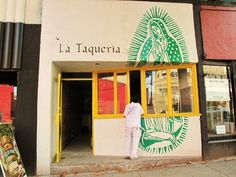 a person standing in front of a building with the word la taqueria painted on it