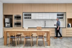 a man is walking in the kitchen next to a table