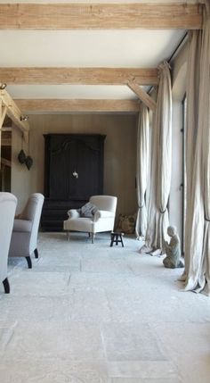 a living room filled with furniture and covered in draping on top of wooden beams