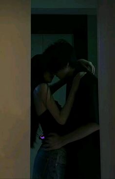 a man and woman embracing each other in front of a door with the light on