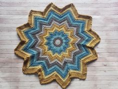 a blue and yellow crocheted doily sitting on top of a wooden floor