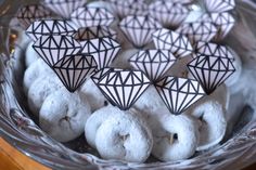 some white donuts with black diamond decorations in a glass bowl on a wooden table