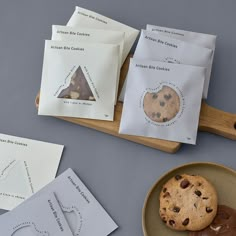 chocolate chip cookies are on a plate next to some envelopes