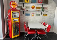 an old fashioned gas pump sits in the corner of a room with red chairs and a white table