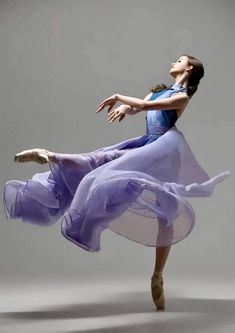 a woman in a purple dress is dancing with her arms spread out to the side