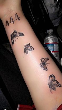 a woman's arm with butterflies on it and chinese characters tattooed on the wrist