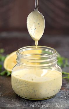 a glass jar filled with liquid sitting on top of a table next to lemon wedges