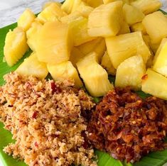 a green plate topped with sliced pineapples and other food