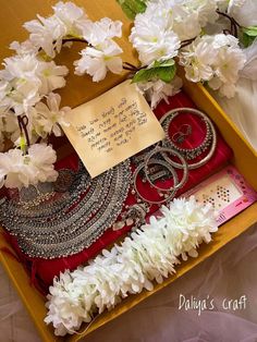 a box filled with jewelry next to white flowers