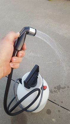 a person is holding a blow dryer in their hand and spraying water on the ground