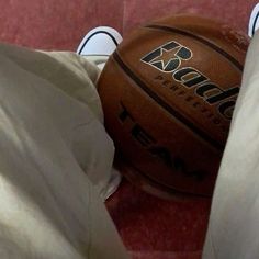 a basketball sitting on top of a red floor next to a pair of white shoes