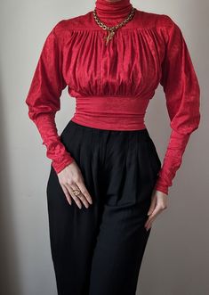 Sublime vintage blouse dating from the 1980s, a creation by the French luxury fashion house Chantal Thomass. It's an incredible model, with a beautiful, passionate red color that will illuminate all skin tones. Its cut is spectacular, with its belted waist and high collar with a very aristocratic look. The sleeves are cut in a lamb shape, with slightly puffed shoulders and tightened cuffs. Magnificent pleated work decorates the entire bust, meticulous artisanal work. It closes with an invisible Red Long Sleeve Blouse For Evening, Retro Red Top For Party, Retro Red Party Tops, Red Retro Party Tops, Retro Red Party Top, Red Retro Party Top, Retro Long Sleeve Evening Blouse, Retro Long Sleeve Blouse For Evening, Vintage Long Sleeve Evening Tops