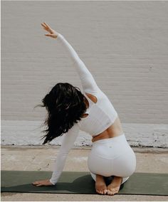 a woman in white doing yoga poses on a mat with her arms stretched out to the side