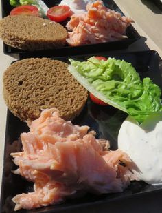 two black trays filled with different types of food