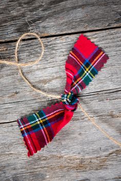 a red and green plaid tie tied to a piece of string on top of wooden planks