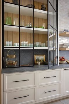 a kitchen with white cabinets and shelves filled with glassware on top of it's counters