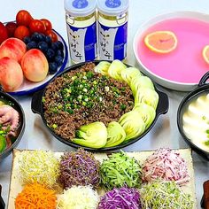 a table topped with lots of different types of food next to cans of sodas