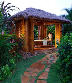 a woman sitting in a wooden gazebo surrounded by greenery