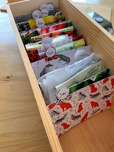 an open drawer filled with lots of different types of cards and envelopes on top of a wooden table