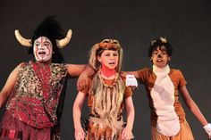 three children dressed in costumes standing on stage