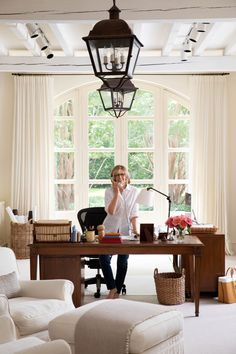 a woman sitting at a desk in front of a window talking on her cell phone