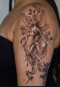 a woman's shoulder with a tattoo design on her arm and the image of a fairy holding flowers