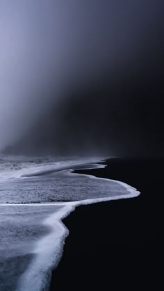 an ocean beach with waves coming in on the shore and foggy skies above it