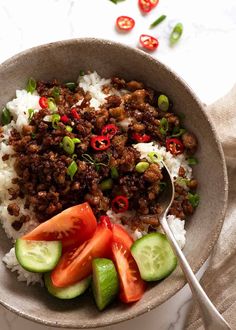 a bowl filled with rice, cucumbers and ground beef next to a spoon