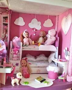 there are many dolls in the doll house with pink furniture and accessories on the table