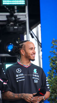 a man with dreadlocks standing in front of a microphone