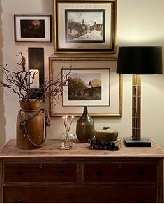 a table with some pictures on the wall and candles in vases next to it