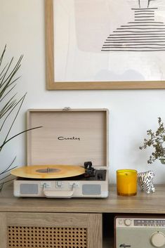 an old record player sitting on top of a wooden table next to a vase with flowers